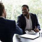 A businessman smiles as he shakes a customer’s hand.